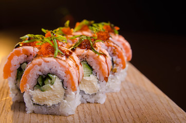 Beautiful sushi rolls with tuna on a wooden plank. Japanese sushi with fish in the Ukrainian seafood restaurant. Menu rolls on a black background