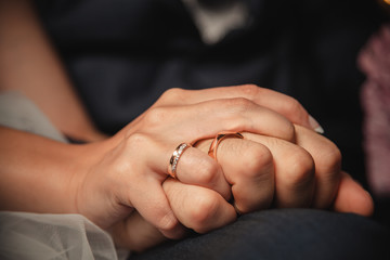 wedding rings in hands of newlyweds