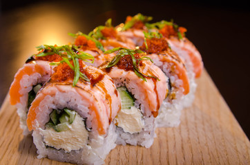 Beautiful sushi rolls with tuna on a wooden plank. Japanese sushi with fish in the Ukrainian seafood restaurant. Menu rolls on a black background
