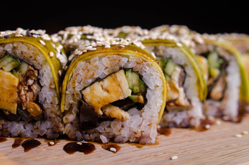 Japanese sushi rolls in the Ukrainian seafood restaurant. Sushi with tuna and avocado sprinkled with sesame. Rolls on a wooden plate with sauce