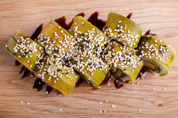 Japanese sushi rolls in the Ukrainian seafood restaurant. Sushi with tuna and avocado sprinkled with sesame. Rolls on a wooden plate with sauce