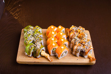 Menu of Ukrainian seafood restaurant. Japanese sushi rolls. Sushi set maki with shrimp,  tuna, eel and avocado. Dish on a wooden plate sprinkled with sesame