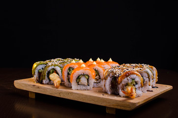 Menu of Ukrainian seafood restaurant. Japanese sushi rolls. Sushi set maki with shrimp,  tuna, eel and avocado. Dish on a wooden plate sprinkled with sesame