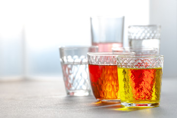 Various lemonades in glass faceted glasses on a gray table. Background image.