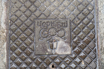 Close up of hatch (luke) in Chernivtsi, Ukraine. Metal rusty manhole cover in Bukovina, Eastern Europe. Grunge and texture concept. Translation: "Chernivtsi" (name of the city)