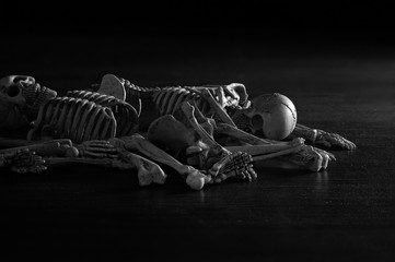 Pile of human bones on dark brown wooden and adjustment color black and white for background.