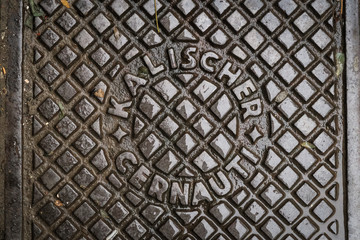 Close up of hatch in Chernivtsi, Ukraine. Metal rusty manhole cover. Translation: "Kalisher Chernivtsi" (name of the manufacturer's factory and name of the  city in Romanian)"