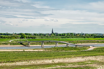 View across the floodplains of the river Waal near Nijmegen, The Netherlands with the Zaligebrug pedestrian bridge across the new river Channel and the church tower of Lent in the distance
