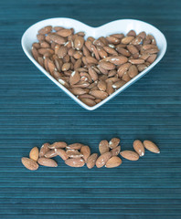 Nuts arranged in heart  on background. Healthy Food image close up almond on the cup plate. Love Texture on top view mock up
