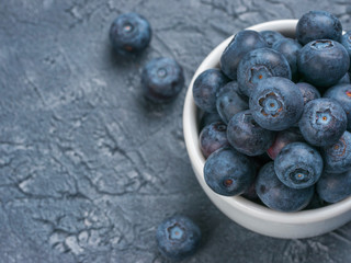 Freshly picked blueberries closeup. Ripe and juicy fresh blueberry on textured concrete background. Bilberry on gray background with copyspace. Top view or flat lay