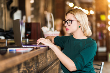 Portrait of pretty young business woman in glasses sitting on workplace