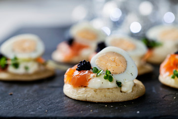 Party food, blinis with salmon, quail egg and caviar