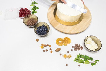 Confectioner smooths white cream on a biscuit cake with a cooking spatula. The concept of homemade pastry, cooking cakes.