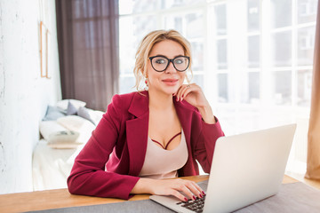 Young female entrepreneur sitting at table in her home office working on laptop