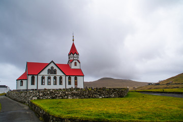 View of iconic Scandinavian church with red roof. Located in Sandavágur village, Vágar Island. Popular tourist spot in Faroe Islands, Denmark, Europe.