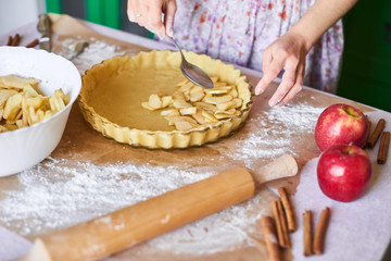 Home baking of holidays classic sweet pies. Woman hands fixing pastry dough in a tray and pumpkin pie ingredients. Preparing traditional desserts