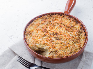 Close up view of appetizing potato casserole with fish, eggs and cream. Potato casserole in serving baking pan on white concrete background