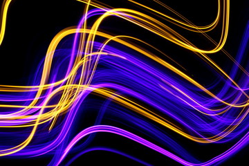 Long exposure, light painting photography.  Vibrant streaks of neon purple and metallic gold color against a black background.