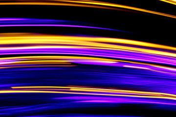 Long exposure, light painting photography.  Vibrant streaks of neon purple and metallic gold color against a black background.