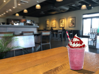 Strawberry frappuccino whip cream and souce on wooden table at cafe