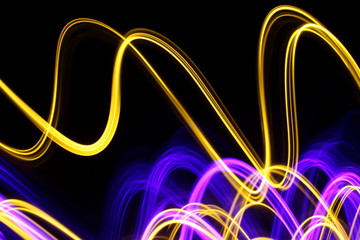 Long exposure, light painting photography.  Vibrant streaks of neon purple and metallic gold color...