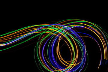 Long exposure, light painting photography.  Vibrant multicolor streaks of neon color against a black background.