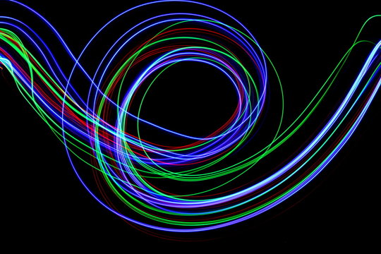 Long exposure, light painting photography.  Vibrant colorful streaks of neon color against a black background.