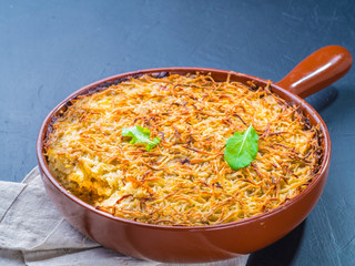 Close up view of appetizing potato casserole with fish, eggs and cream. Potato casserole in serving baking pan on dark concrete background