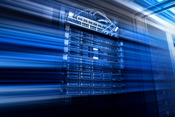 Blade server in rack cluster hard drives storage tapes in internet data center room motion blue
