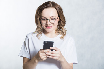Perplexed and worried, a beautiful young woman is holding a smartphone, stares with surprised expression.