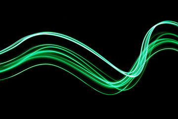 Long exposure, light painting photography.  Vibrant waves of neon green color against a black...