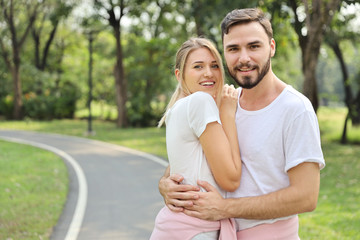 Fototapeta premium young caucasian couple are in love. man and girl wearing white shirt hugging in the park during summer season with smiling and happy face
