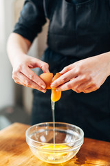 Female chef cracking eggs into a glass bowl