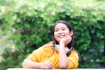 Fototapeta premium Happy smiling primary schoolgirl in casual clothing with headphones on her neck.