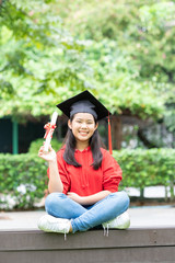 Portrait of cute schoolgirl with graduation hat holding certificate