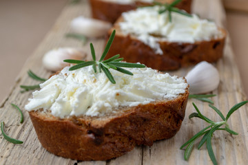 Sliced bread with light cheese on a wooden board.