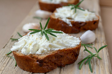 Sliced bread with light cheese on a wooden board.