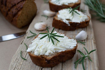 Sliced bread with light cheese on a wooden board.