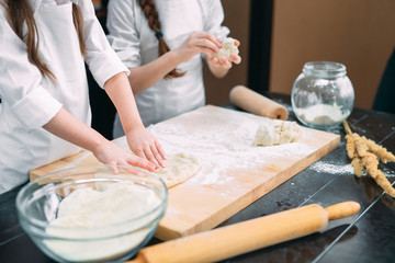 Fototapeta na wymiar funny girls kids are preparing the dough in the kitchen.