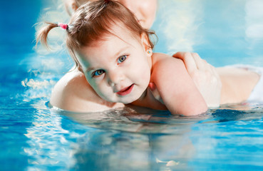 Mom and baby swim in the pool.