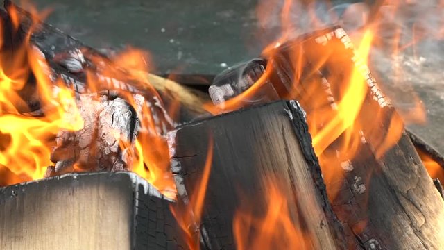 Wood burning slowly with orange fire flame in barbecue grill. Slow motion shot.