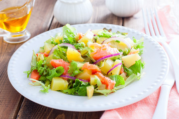 Potato salad with salmon on a white plate on a wooden table, selective focus