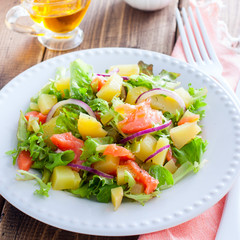 Potato salad with salmon on a white plate, selective focus