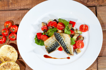 Mackerel baked with lemon, cherry tomatoes, vegetables and spices.