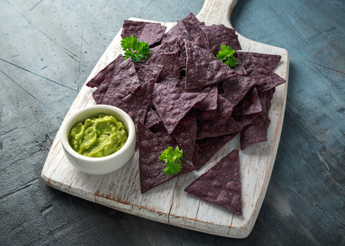 Blue corn Organic tortilla chips with Guacamole on white wooden board