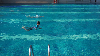 Asian boy swimming in the competition with warm sunlight from the left side.Selected focus. Wide...