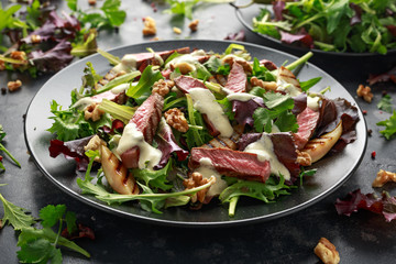 Grilled Beef Steak salad with pears, walnuts and greens vegetables and blue cheese sauce. healthy food.