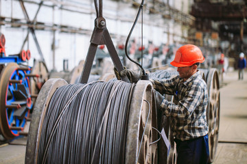 Wire rod, fittings in warehouses. worker alongside a bundle with catalkoy. industrial storehouse at the metallurgical plant.