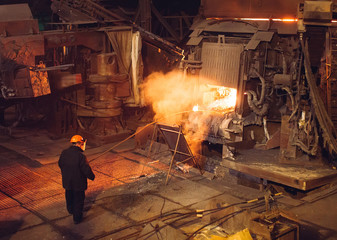 Plant for the production of steel. An electric melting furnace. Factory worker takes a sample for metal.