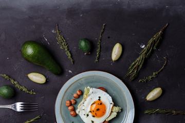 Top view of healthy breakfast scrambled eggs with bread and nuts in a plate on black background with avocado, rosemary, lime. Top view. Flat lay. Healthy food, diet, fitness